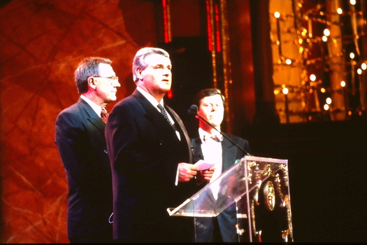 Two CEOs at the lectern whilst Ray Martin watches on