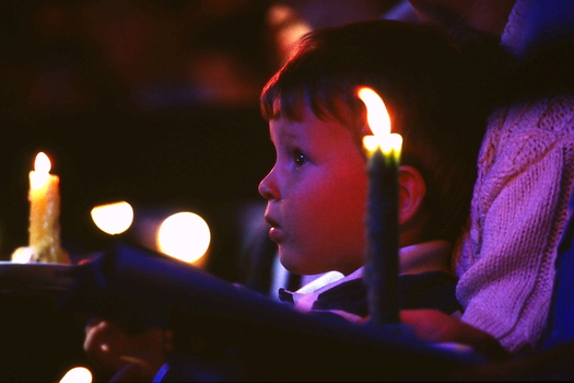 Boy looking toward stage with candles around him