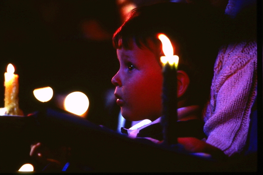 Boy looking toward stage with candles around him
