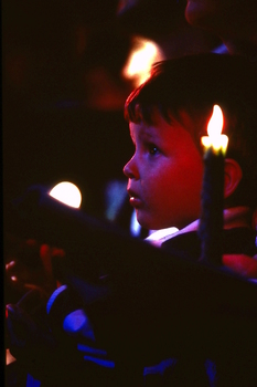 Boy looking at stage with candles around him