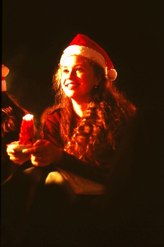 Girl holding candle and wearing Santa hat