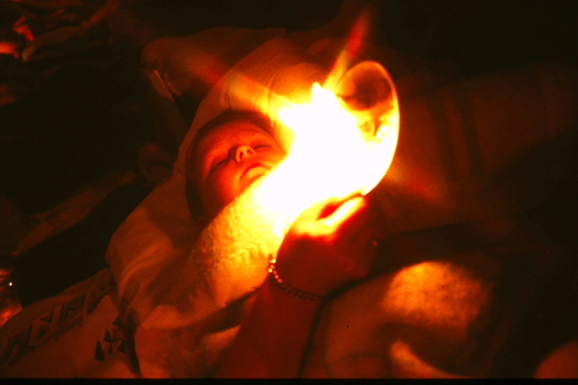 Child wrapped in blankets holding candle