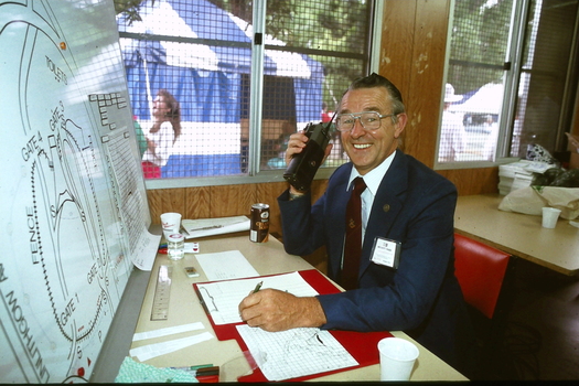 Seated man on walkie talkie with diagram of ground in front of him
