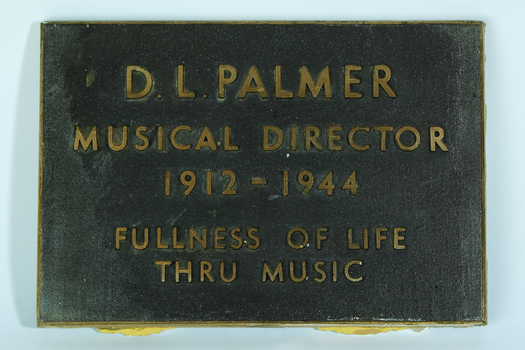 Large text in gold on brown plaque