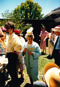 Staff member with Eastern bonnet stands in the middle of a crowd