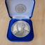 Silver coloured medallion in blue velvet box