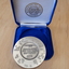 Silver coloured medallion in blue velvet box