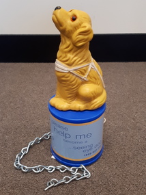 Yellow dog with brown eyes stares upwards whilst sitting on blue cylinder