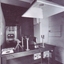 Behind shooting table with rifle in frame and target down narrow corridor