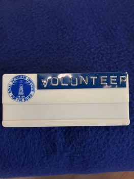White plastic badge with RVIB logo in top left hand corner