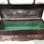 Battered small brown suitcase with green felt attached to base