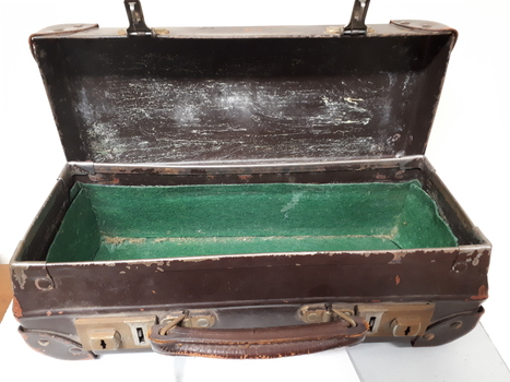 Battered small brown suitcase with green felt attached to base