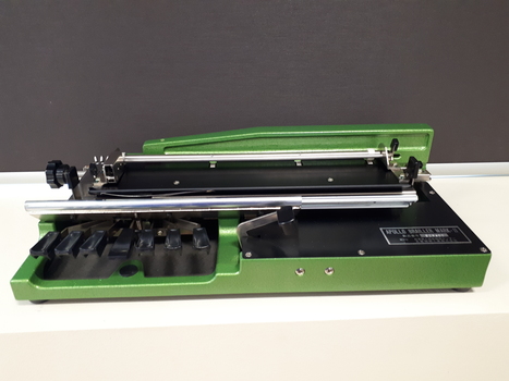 Bright green metal base supporting silver Braille with black keys.
