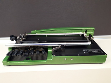 Bright green metal base supporting silver Braille with black keys.