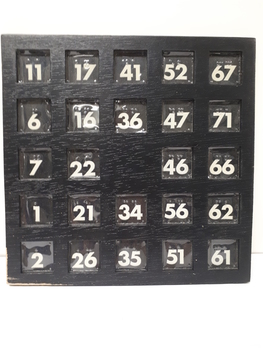 Black wooden board with cutouts for paper numbers