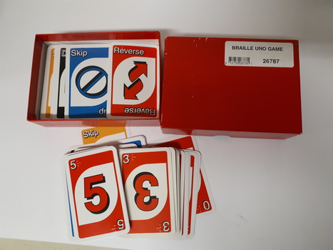 UNO playing cards with braille embossed on top left-hand and bottom right-hand corners in red cardboard box.