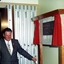 Man in suit with gold chain of office holding draw cord that revealed plaque