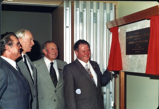 Four men in suits looking at plaque