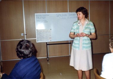 Woman standing in front of white board speaking to audience
