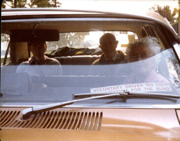 Three people sit in a car driven by a volunteer
