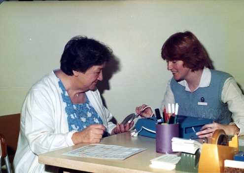 Two women looking at a TBM and speaker attached to it