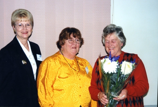 Edna Allen holds flowers as Di Kerr and another volunteer stand beside her