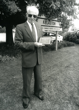 Roy King holds a plaque outside Kelaston