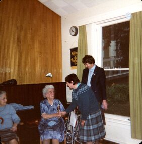 Woman in kilt shakes hand of an older woman