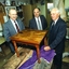 Two men hold a side table whilst a third man looks on 