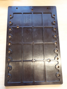 Brown plastic rectangular hand frame with holes evenly spaced on either long side.