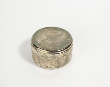 Small round silver tin with inscription on lid and tea candle inside