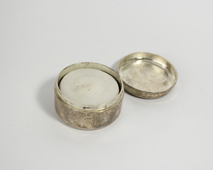 Small round silver tin with inscription on lid and tea candle inside