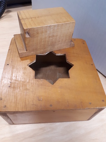 Wooden box with eight-sided star shape cut out in middle, and wooden rectangular block
