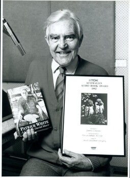 Narrator James Condon in the recording studio with the book and his award