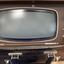 Small television screen in black case, with long rectangular cabinet.