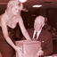 Blonde woman handing John Wicking a wrapped present