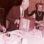 John Wicking looking at his wrapped gift, with Eunice Wilson looking on