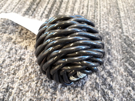 Black tubing woven into shape of cricket ball with bell inside