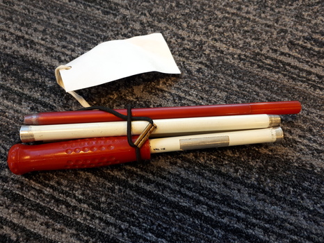 Metal cane folded into three sections and tied with band