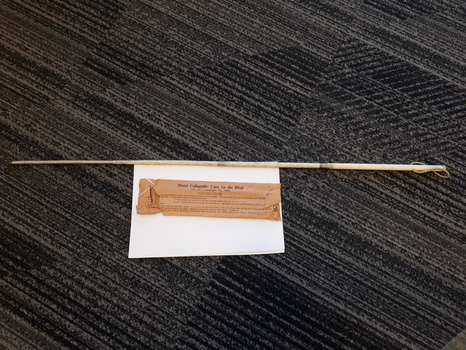 White metal cane and brown paper packet with labelling