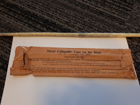 White metal cane and brown paper packet with labelling