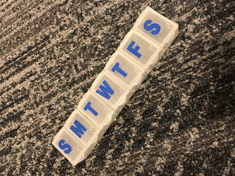 Plastic container with seven sections, each labelled with letter in print and Braille
