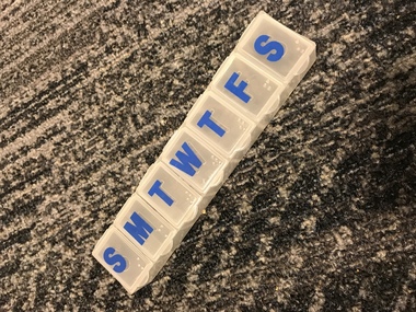 Plastic container with seven sections, each labelled with letter in print and Braille