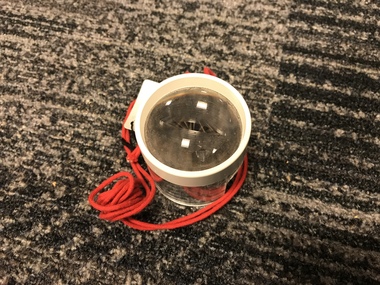 Raised circle with lens in top end and red cord for wearing around the neck