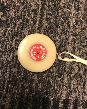 Cream disk with measuring tape inside and red label