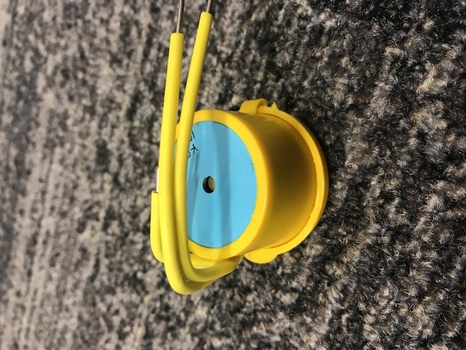 Yellow round container with two metal prongs covered in plastic