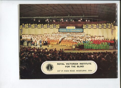 Colour photograph of the choirs on stage at Carols whilst the compere speaks to a girl with a violin who is about to perform