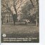 Photograph of front of building looking across grassed area through trees