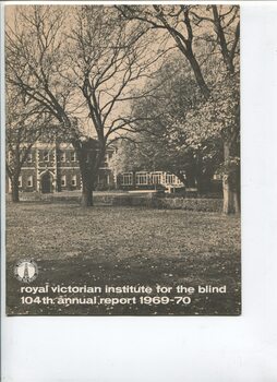 Photograph of front of building looking across grassed area through trees