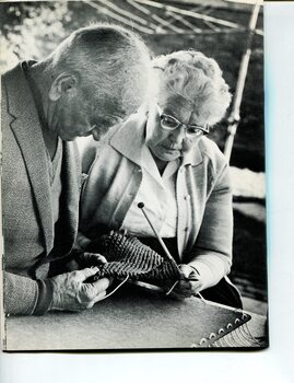An older man feels the yarn that his companion has knitted